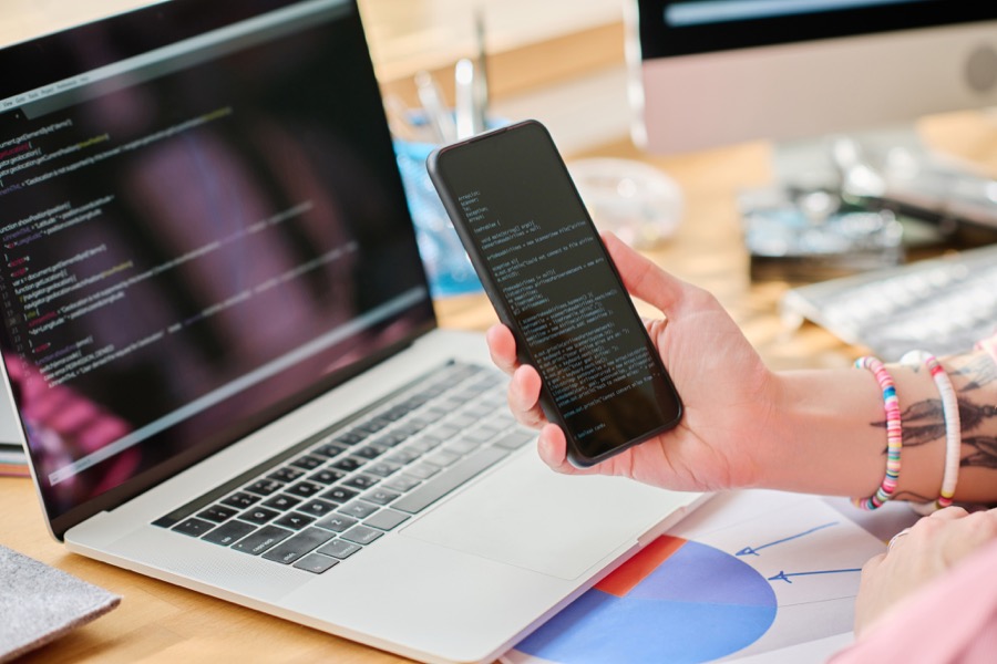 Ajroni developer reviewing code on a laptop and smartphone