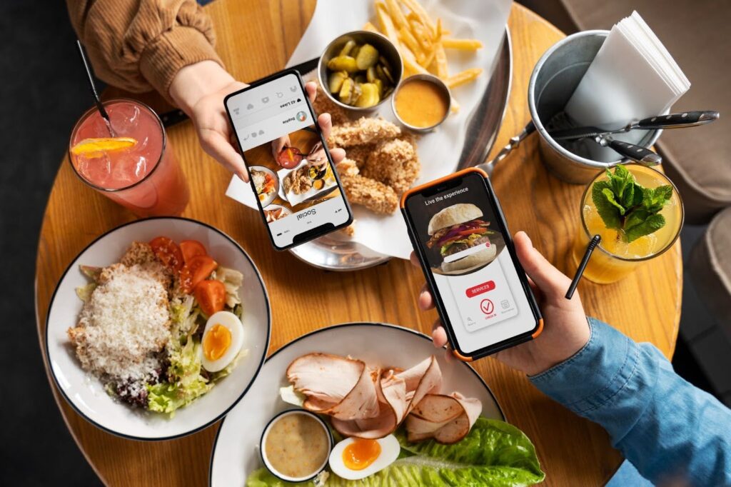 People using smartphones for online ordering at a restaurant table with shared food and drinks.